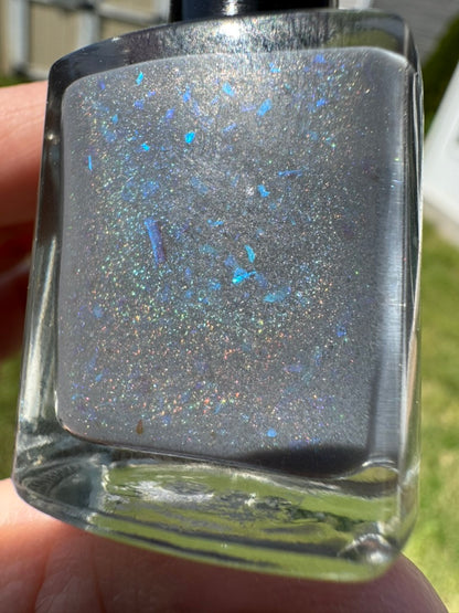 Nail polish bottle with glittery finish held by a hand. Opal theory polish To Artemis with love