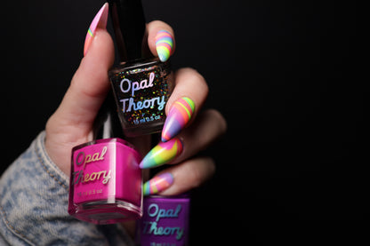 Hand with colorful nail polish holding Opal Theory nail polish bottles against a black background