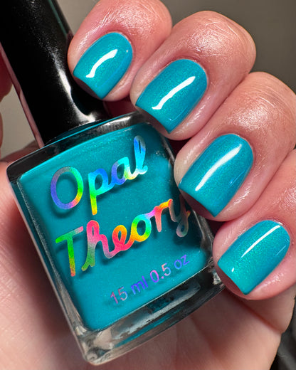 Turquoise nail polish with 'Opal Theory' branding held by a hand with matching nails.