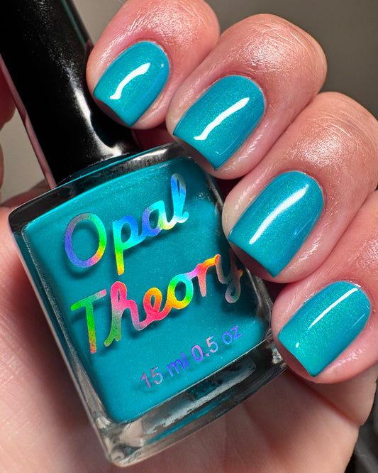 Turquoise nail polish with 'Opal Theory' branding held by a hand with matching nails.